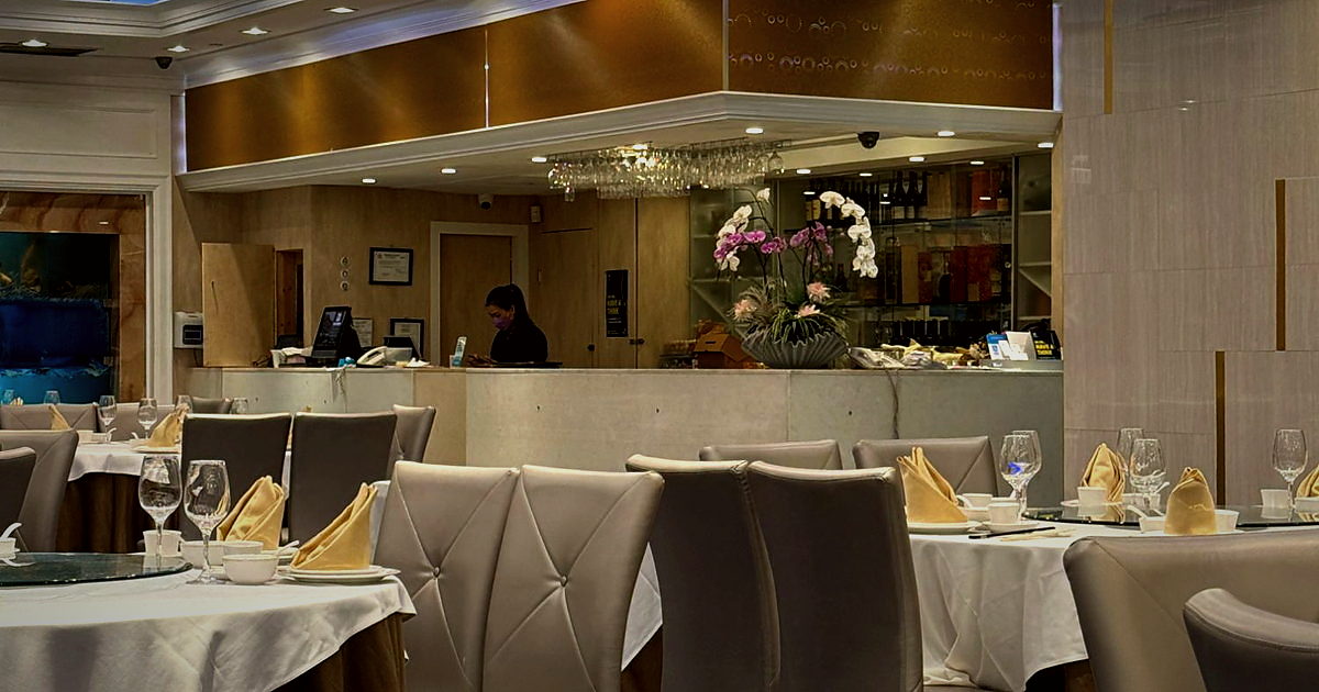 The main dining room at Shun Feng — orchids at the host stand, set tables and the gold ceiling